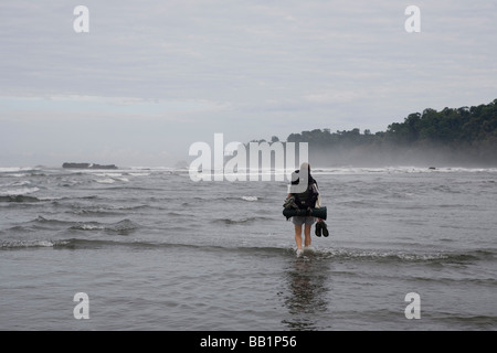 Ein Wanderer überquert einen Fluss entlang der Küste in Corcovado Nationalpark, Costa Rica. Stockfoto