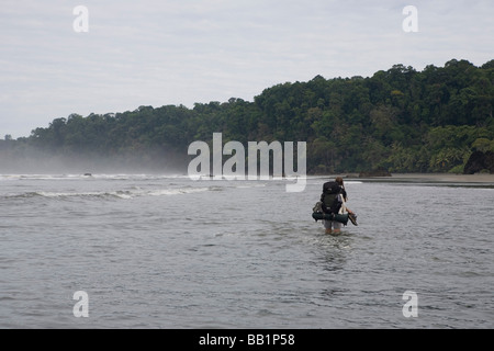 Ein Wanderer überquert einen Fluss entlang der Küste in Corcovado Nationalpark, Costa Rica. Stockfoto