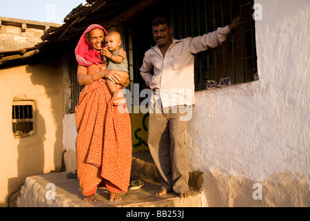 Einen typischen ländlichen Haus und Familie in der Gujarati-Stadt von Sasan, Indien. Die Frau in einem roten Sari hält ihren Enkel. Stockfoto