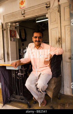 Schneider in der Gujarati Stadt Rajkot, Indien. Er sitzt draußen auf der Veranda seines Unternehmens. Stockfoto