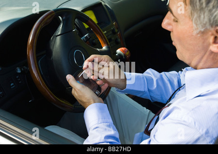 Mann mit einer personenbezogenen Daten-Assistenten in einem Auto Stockfoto