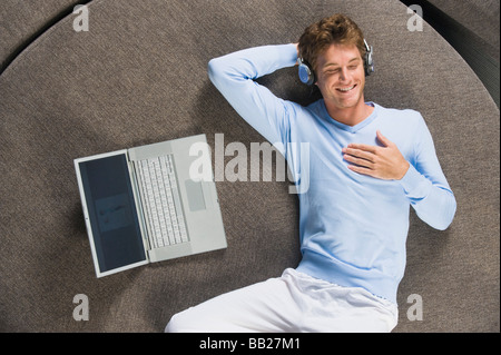 Mann auf ein rundes Sofa liegend und Musik hören Stockfoto