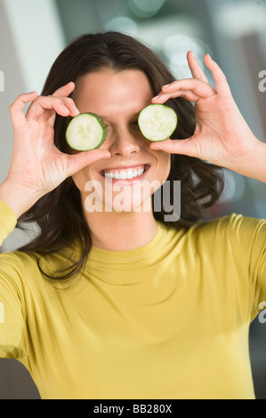 Frau mit Gurkenscheiben vor ihren Augen Stockfoto