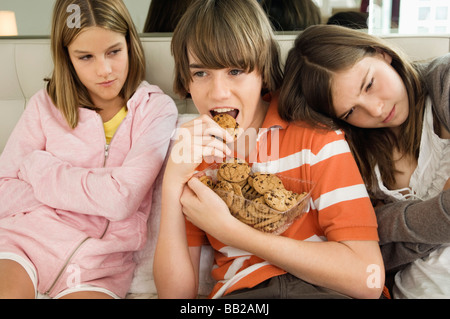Junge Schokoladenkekse mit zwei Mädchen neben ihm Essen Stockfoto