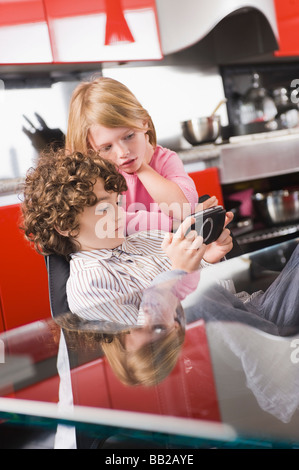 Spielen ein Videospiel und seine Schwester neben ihm stehenden jungen Stockfoto