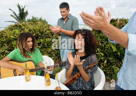 Man spielt eine Gitarre und seine Freunde ihm applaudieren Stockfoto