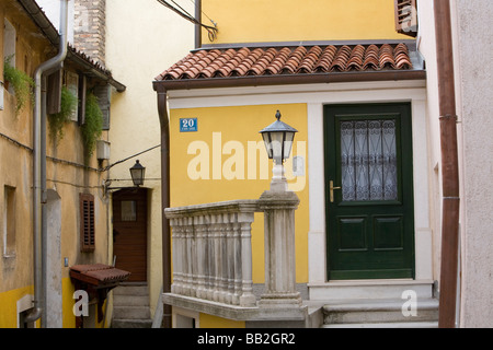 Reisen in Kroatien; eine grüne Tür auf ein gelbes Haus auf einer schmalen Straße im alten Dorf von Lovran. Stockfoto