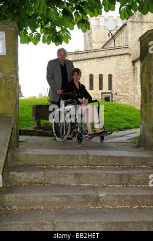 Rollstuhlfahrer und Betreuer am oberen Rand einer Treppe Stockfoto