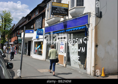 Ein geschlossen nach unten laden zu lassen mit einer Frau zu Fuß vorbei an der Ladenfront im Banstead High Street Surrey UK Stockfoto