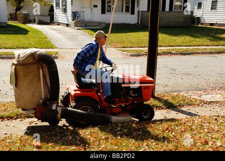 Mann auf Traktor aufräumen Blätter mit einem Vacum Bagger auf Rückseite Stockfoto