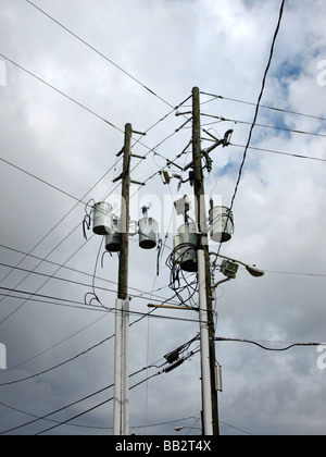 Strommast Masten und Drähte mit Kondensatoren Straßenlaterne gegen grauen Himmel und Wolken Stockfoto