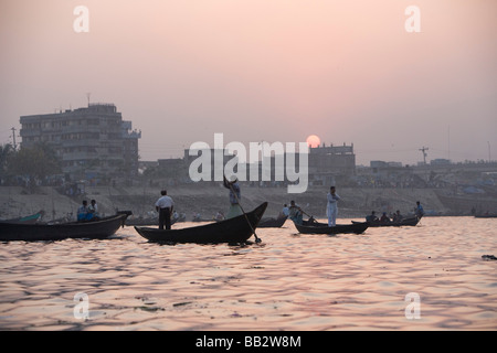 Alltag in Bangladesch; Viele kleine Ruderboote arbeiten bei Sonnenuntergang am Fluss Buriganga in Dhaka. Stockfoto