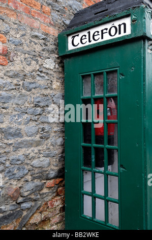 Traditionelle irische grüne Telefon Box Seitenansicht, aus rote Backstein alte unbenutzte stillgelegten Baufälligkeit Wand veraltete Technologie Stockfoto