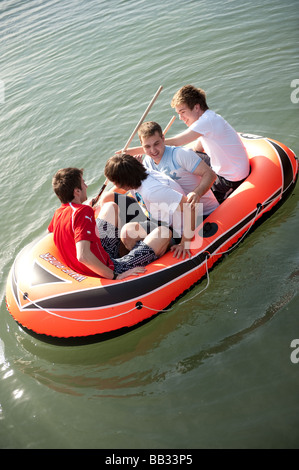 Vier junge Männer Teenager Studenten an der Aberystwyth University Spaß auf dem Wasser paddeln in ein Schlauchboot, Wales UK Stockfoto