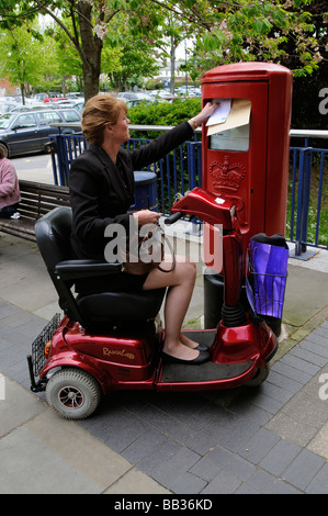 Weibliche Mobilität Scooter Fahrer buchen einen Brief im Stadtzentrum Stockfoto