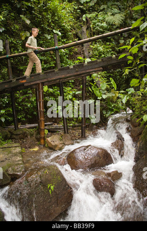 Südamerika, Ecuador, El Pahuma Orchidee Reserve.  Junge (9 Jahre) Kreuzung Brücke in üppigen Nebelwald in der Nähe Botanischer Garten.  HERR Stockfoto