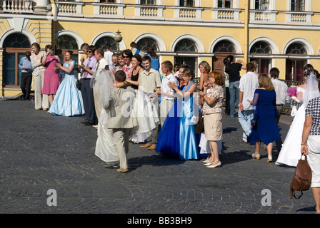 Ein Bräutigam trägt seine Braut über eine Linie der Hochzeitsgäste in den Straßen von St. Petersburg, Russland Stockfoto