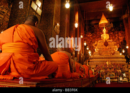 THAILAND, Bangkok. Gruppe von buddhistischen Mönchen beten in ihrem traditionellen orange Kleid sitzen im Lotussitz in einem Tempel Stockfoto