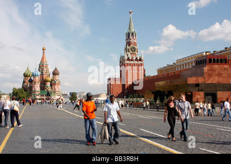 An einem sonnigen Sommertag auf dem Roten Platz in Moskau spazieren schwarze Studenten in der Stadt der russischen Hauptstadt von der Basilius-Kathedrale zum Manezhnaya-Platz. Stockfoto