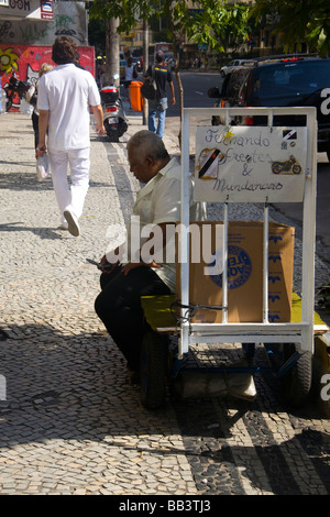 Ein älterer Brasilianer tippt eine SMS-Nachricht auf seinem Handy auf einem Bürgersteig des Viertels Copacabana, Rio De Janeiro, Brasilien. Stockfoto