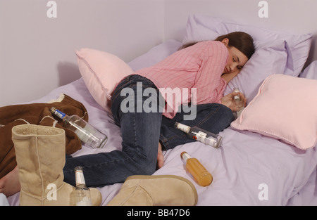 ein junges Mädchen betrunken und schlafend auf einem Bett Stockfoto