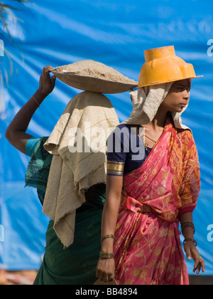 Weibliche Arbeiter auf einer Baustelle tragen Zement in Stahl Schalen, auf ihren Köpfen in Bangalore, Karnataka, Indien Stockfoto