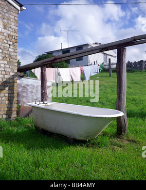 Eine Badewanne steht im Freien in der Nähe von Wäsche. Stockfoto