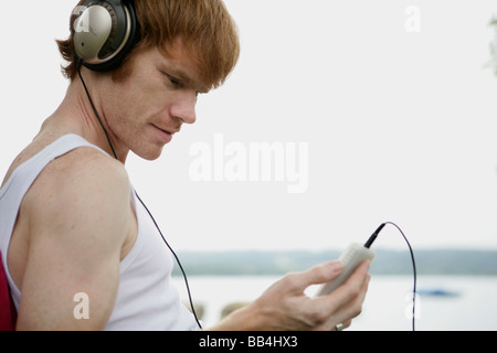 junger Mann mit Kopfhörer mit mp3-Player auf dem See Stockfoto