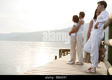zwei Paare stehen auf einem Steg am See Stockfoto