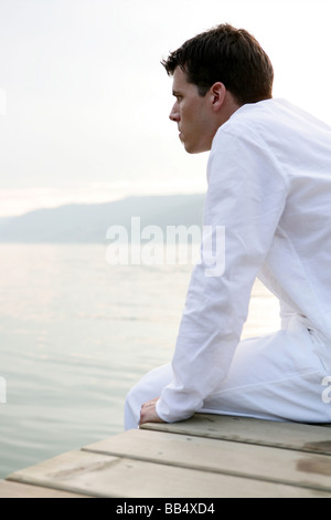 Mann sitzt auf einem Steg am See Stockfoto