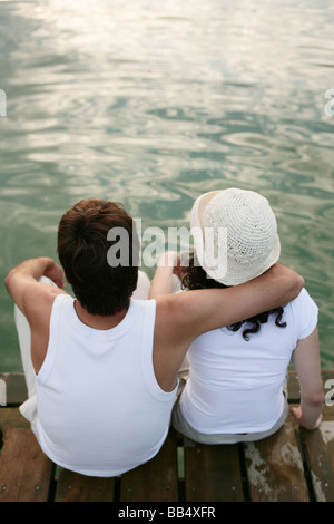 ein paar sitzt auf einem Steg am See Stockfoto