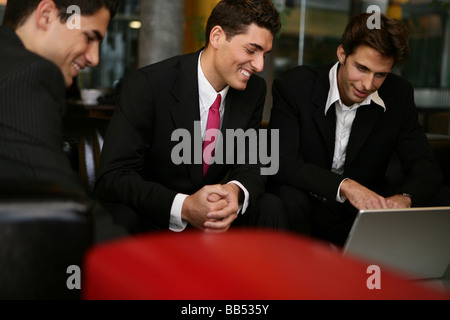 drei Männer suchen auf einem Laptop in eine lounge Stockfoto