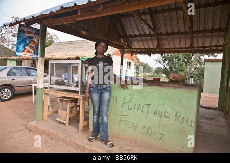 Eine junge Frau grillt Fisch an einem Straßenrand "point and kill" Fisch Stand im Millenium Park in Abuja, Nigeria. Stockfoto