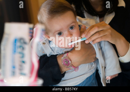 6 Monate altes Baby waschen seine Zähne mit seiner Mutter Stockfoto