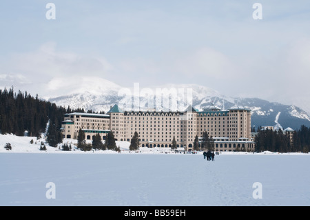 Das Fairmont Chateau Lake Louise Hotel umgeben von schneebedeckten Bergen und mit Blick auf den zugefrorenen See Stockfoto