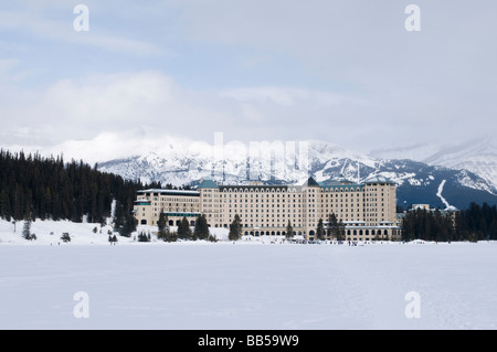 Das Fairmont Chateau Lake Louise Hotel umgeben von schneebedeckten Bergen und mit Blick auf den zugefrorenen See Stockfoto