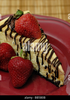 Käsekuchen mit Schokolade beträufelt und garniert mit Erdbeeren Stockfoto
