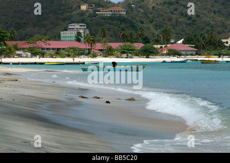 Ansicht des Grand Anse Beach mit einem Fischer Entleerung seinem Fischerboot der jüngsten fangen, Grenada, Karibik. Stockfoto