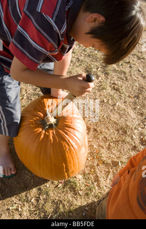 Junge mit einem Messer Kürbis schnitzen, erstelle ich eine Jackolantern für Halloween Stockfoto