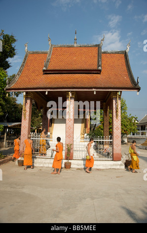 Buddhistische Mönche gehen über ihre täglichen Aufgaben des Tempels zu Reinigungs- und Wartungsarbeiten in Luang Prabang Stockfoto