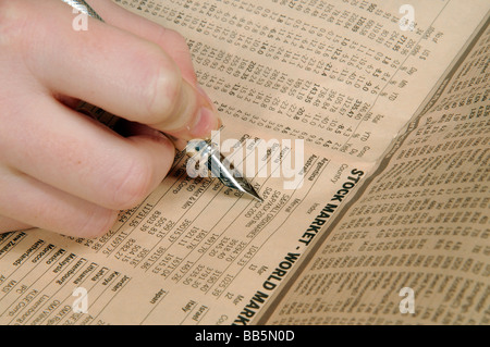 Hand, die einen Silberstift Weltmarktpreise von einer Finanzzeitung Seite überprüfen Stockfoto