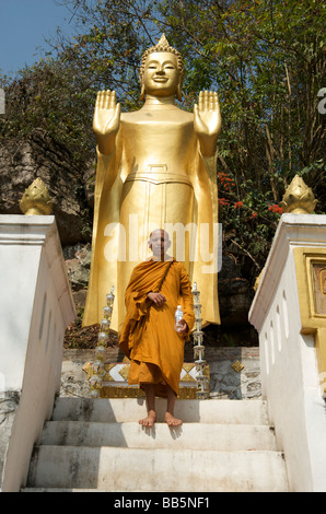 Ein buddhistischer Mönch steht vor einer Buddhastatue auf die Stufen hinauf auf Phou Si Hügel oberhalb von Luang Prabang Laos Stockfoto