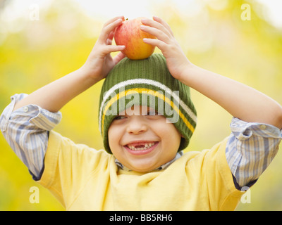 Zahnlose Hispanic junge Apfel auf dem Kopf balancieren Stockfoto