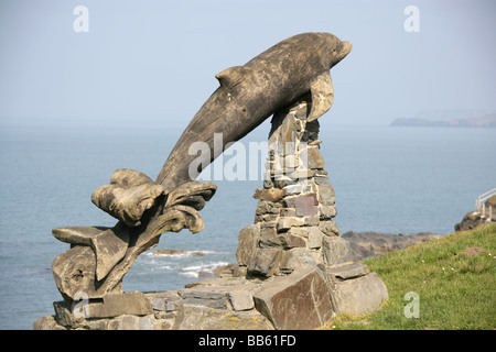 Dorf von Aberporth, Wales. Paul Clarke entworfen und geschnitzt springenden Delfin Skulptur mit Blick auf Aberporth Küste. Stockfoto