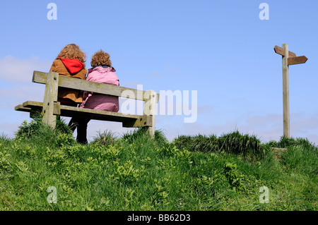 Zwei weibliche Wanderer ruht auf einer Bank, in der Nähe ein Schild, ein heller Europäischer Frühling Stockfoto