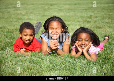 Drei Kinder im Rasen Lächeln verlegen Stockfoto