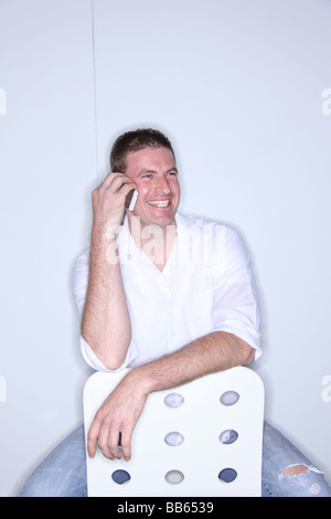 Mann sitzt in moderner Stuhl mit Handy lachen Stockfoto