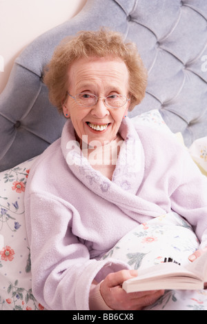 Im Bett mit Buch entspannende Senior Woman Stockfoto