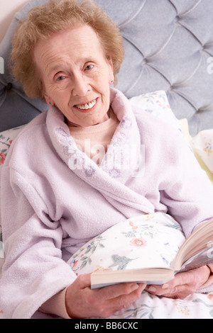 Im Bett mit Buch entspannende Senior Woman Stockfoto