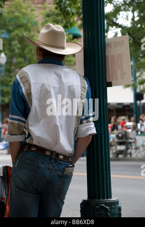 Cowboy lehnte sich gegen einen Laternenpfahl in einer kleinen Stadt, warten auf eine parade Stockfoto